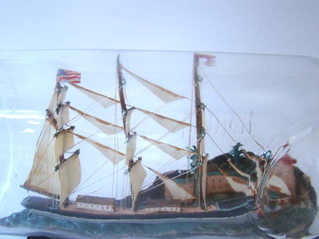 A large Ship in a bottle, the background featuring a coastal town with trees and a lighthouse, American circa 1940 — image 2